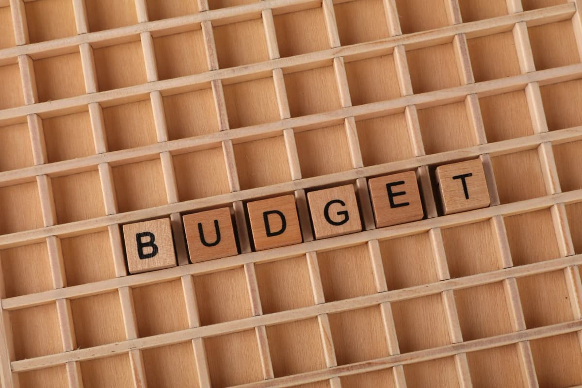 Wooden letter tiles spelling 'budget' on a wooden grid background, symbolizing finance and planning.